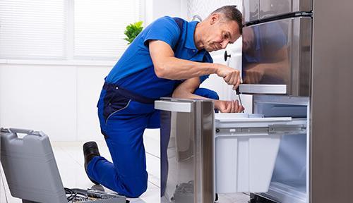 Repair technician fixing freezer drawer