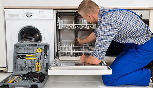 a technician repairs a dishwasher